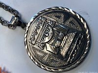 Front side of Aztec embossed silver medallion pendant with warrior design and chain attached