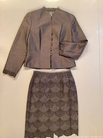 Full view of the jacket and skirt laid flat showing color, design, and lace trim details.