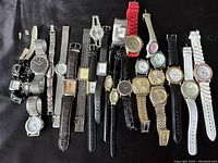Overview of all 24 wristwatches laid out on black surface