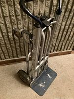 Folded vertical view of the aluminum dolly showing handle grips, frame, and platform