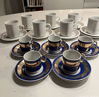 View showing all espresso cups and saucers, vintage set foreground with royal blue and gold trim, IKEA white cups and saucers background with simple stripes.
