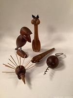 Full view of the five vintage mid-century modern Danish teak animal barware pieces including a crow, cat, fish, porcupine, and caterpillar.