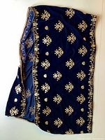 Full view of the royal midnight blue velvet shawl folded to show front embroidery and border edges.