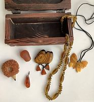 View of all amber jewelry and collectibles arranged next to open wooden chest showing contents and context