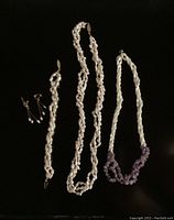 Full view of the set including two seed pearl necklaces, pearl bracelet, and matching earrings laid out on black surface