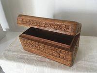 Open angled view of the rectangular wooden trinket box showing intricate floral carvings on the outside and the interior with felt lining.