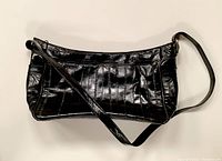 Side view of large black eel skin handbag showing smooth glossy leather and adjustable strap.