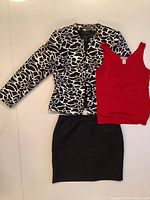 Full view of the suit set laid out, showing the animal print jacket, black skirt, and red cami