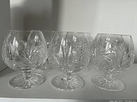 Six hand cut crystal brandy/cognac glasses with pinwheel pattern, 4 inches tall, displayed in a row