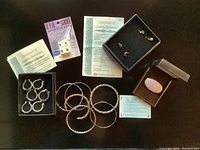Collection of sterling silver and brass/copper/silver bracelets paired with Publishers Clearing House earrings including comfort studs and an agateware pottery brooch with hairline crack.
