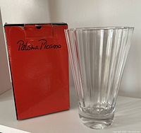 Front view of the clear ribbed crystal vase alongside its original red box with Paloma Picasso logo.