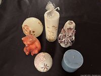 Overview of six vintage candles showing the variety including carved candle, teddy bear, dried flower balls, white pillar candle with flowers, and blue candle.