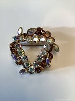 Top view of the vintage aurora borealis rhinestone brooch showing the circular design and rhinestone colors.