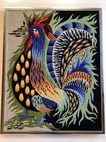 Full front view of large vintage needlepoint rooster artwork showing intricate detailed stitching and vibrant colors, mounted in silver metal and moss green border frame.