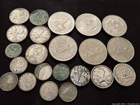 Top view showing all vintage coins arranged on black surface including Canadian $1 coins, silver quarters, dimes, and a 5 cent coin