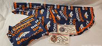 Two handmade aprons with Denver Broncos navy blue, orange, and white logo and text pattern.