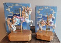 Two Lefton carousel horse figurines on wooden bases with original boxes behind. Larger horse music box works; smaller one does not.