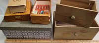 View of multiple decorative boxes stacked: patterned cardboard box, cigar box, two wooden crate style drawer boxes, and boxes of vintage chewing gum inside one drawer.