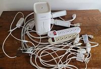 Photo showing 2 power strips, 3 extension cords, plant light and humidifier on wooden table