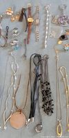 Top view of assorted jewelry including watches, bracelets, rings, pins, key chains, and pendants, showing variety and style
