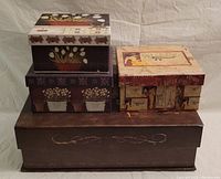 Three stacked decorative boxes with brown and beige motif, floral designs, and Paris-themed artwork