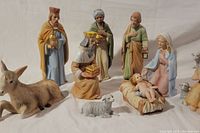 Close-up showing the same group of eleven nativity figurines with soft detailed painting and condition.