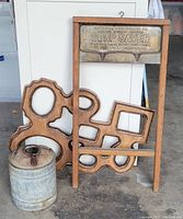 Full lot showing vintage washboard, handmade wooden picture frame, and small metal gas can on concrete floor.