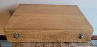 Closed wooden flatware case with metal clasps, rectangular shape showing wood grain finish.