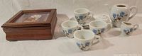 Miniature tea set with 4 cups and jewelry box arranged in a row.