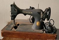 Side view of vintage Singer sewing machine on wooden base, showing Singer logo and gold badge.