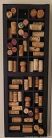 Full view of black wooden shadowbox with various wine corks inside compartments.