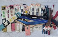 Overview photo showing assortment of vintage zippers in original packaging along with loose zippers in blue, beige, brown, and red.