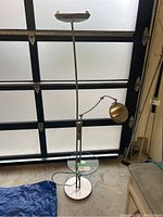 Full view of the floor lamp with two lamps and the glass end table attached to the stand.