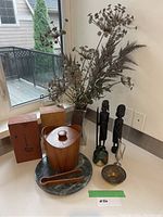 Overview of all items including wooden ice bucket and tongs on marble tray with vase, carved figures, brass bowl, and wooden boxes on white countertop.