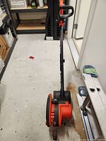 Overview of Black & Decker Edge Hog landscape edger upright on garage floor showing handle, wheels, and blade housing.