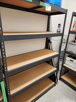 Full view of commercial metal shelf unit with five wooden shelves in side garage/storage space.
