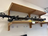 Full view of DaKine roof rack placed on wooden shelves showing the mounting hardware and padded bar.