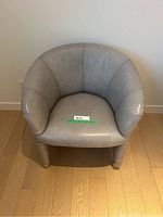 Front view of curved-back accent chair on hardwood floor