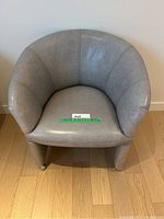 Front view of gray accent chair showing rounded backrest and seat cushion with casters on each leg.