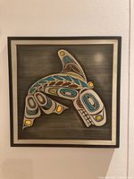 Front view of framed etched aluminum plaque with stylized killer whale design featuring multiple colors on brushed metal background.