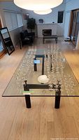 Full view of large rectangular glass dining table with multiple glassware items on top showing the surface and structure.