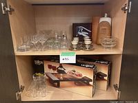 Wide view of the cabinet shelves showing full range of glassware, china cups, decorative bottles and glass bowls.