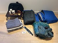 Full lot with sleeping bags, air mattress, bedding, tray table, belts, bags, and small boxed items
