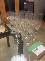 Set of 13 champagne glasses arranged on a glass table, showing 8 Orrefors glasses and 5 additional glasses.