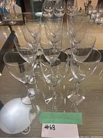 12 clear crystal stemware pieces arranged in two rows viewed from an angle, showing various wine glass styles with long stems and rounded bowls.