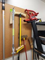 Photo of Toro blower vac and various brooms and brushes hanging on pegboard in garage