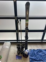 Full view of the ski equipment lot showing skis, poles, boots, helmet, and goggles.