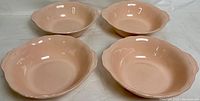 Four large peach-colored ceramic serving/mixing bowls with scalloped edges, top view.