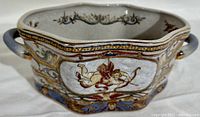 Side view of the ceramic jardiniere showing hand painted cherubs and decorative pattern with handles