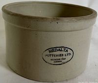 Close-up of Medalta Potteries Ltd. oval stamp on beige stoneware crock indicating origin from Medicine Hat, Alberta.